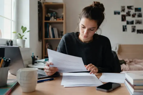 Student čita dokument za radnim stolom prije potpisivanja